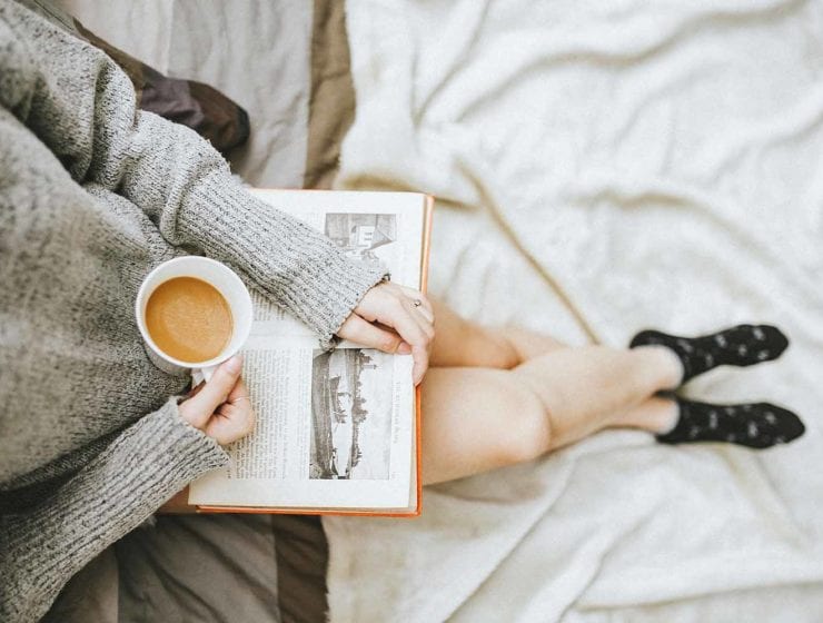 girl reading a book while holding a cup of coffee