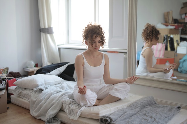 girl sitting on bed and meditating